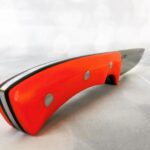 An expertly designed handmade stalking knife has a striking orange and black handle.